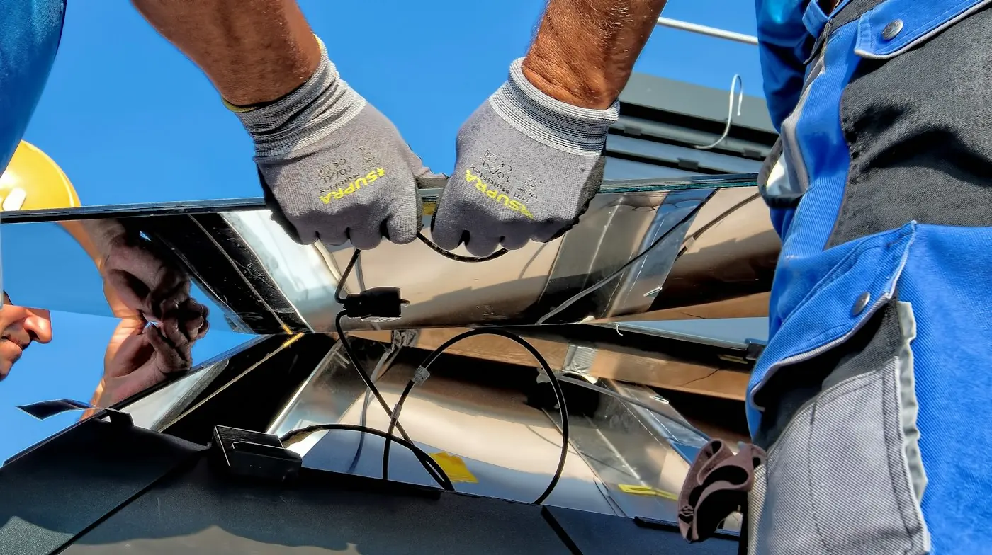 Técnico con guantes conectando el cableado de un sistema solar en un techo